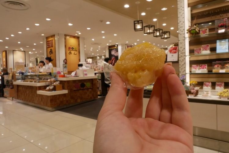 Crispy golden ball held up by hand in front of food stall